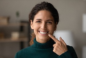 A woman pointing to her bright and beautiful teeth