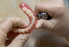 Dental technician filing dentures