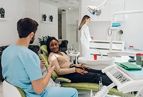 Dentist talking to smiling patient in treatment chair