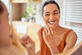 Woman smiling while brushing her teeth