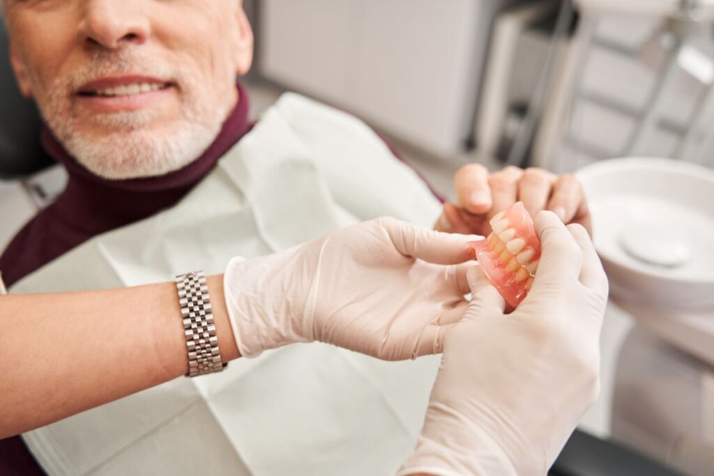 A man looking at new pair of dentures with his dentist